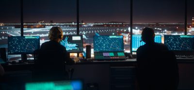 Diverse Air Traffic Control Team Working in a Modern Airport Tower at Night. Office Room is Full of Desktop Computer Displays with Navigation Screens, Airplane Flight Radar Data for Controllers.